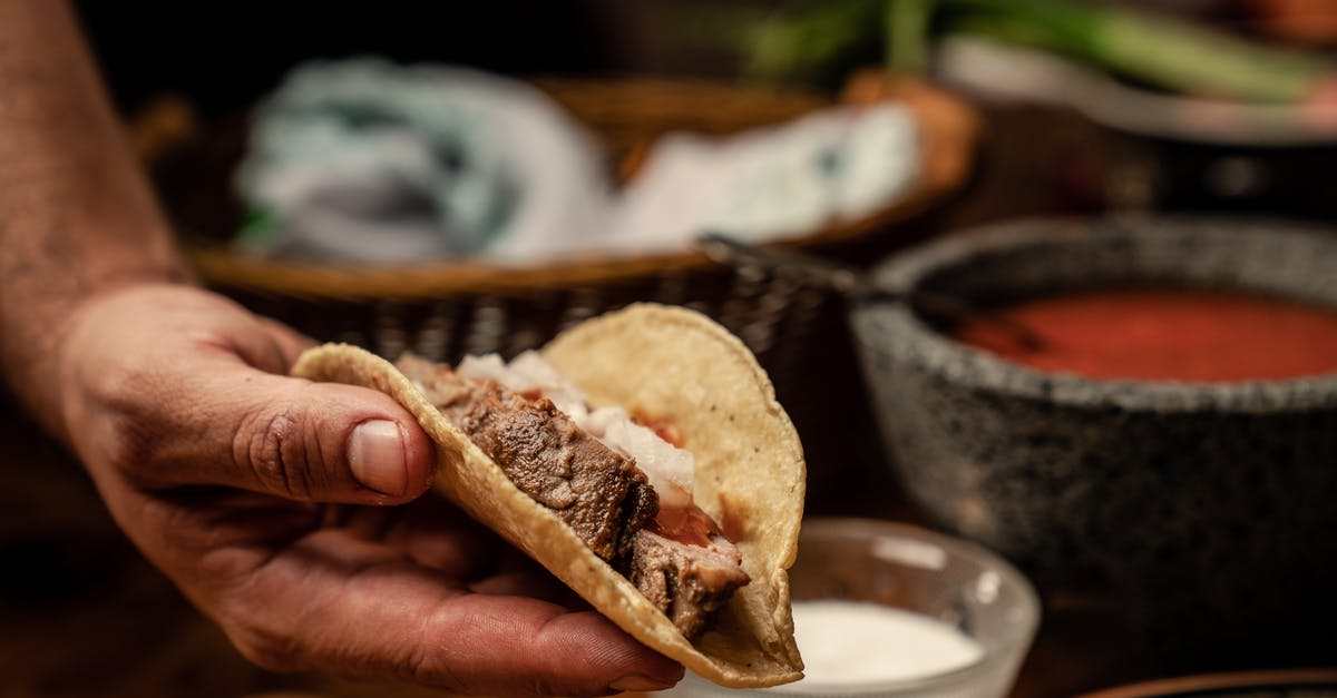 How should I layer the ingredients in a taco salad? - A Person Holding a Taco
