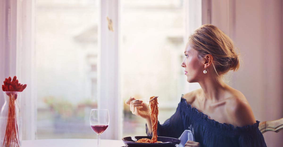 How should red wine be used in Spaghetti Bolognese? - Woman Sitting on Chair While Eating Pasta Dish How should red wine be used in Spaghetti Bolognese? - Woman Sitting on Chair While Eating Pasta Dish
