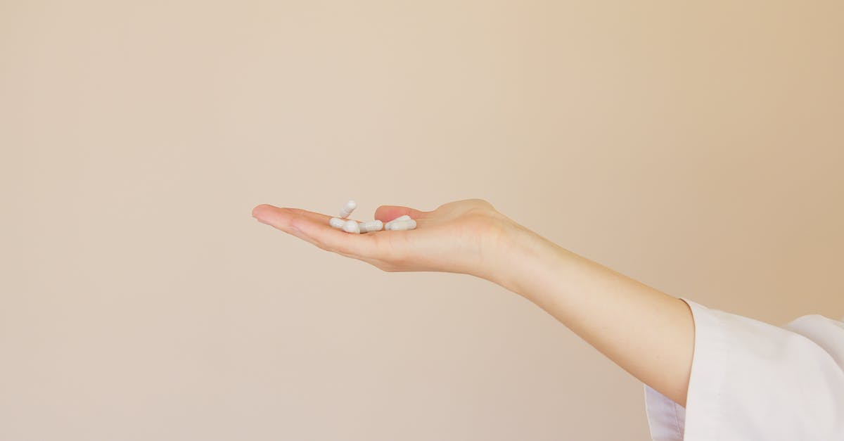 How to add flavour coating to gelatine or starch capsules? - Crop female pharmacist with pile of white pills on palm How to add flavour coating to gelatine or starch capsules? - Crop female pharmacist with pile of white pills on palm