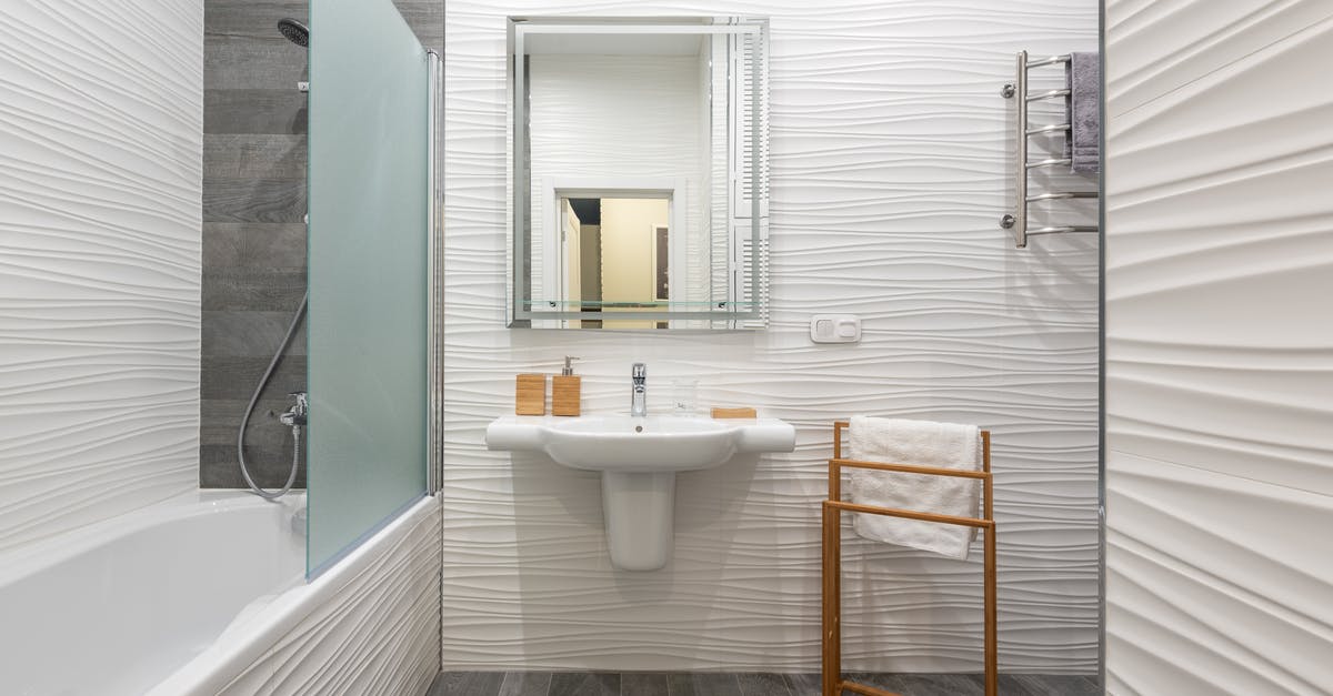 How to broil a rack of goat ribs - Contemporary bathroom interior with bathtub and washstand with toiletry products under mirror in light house