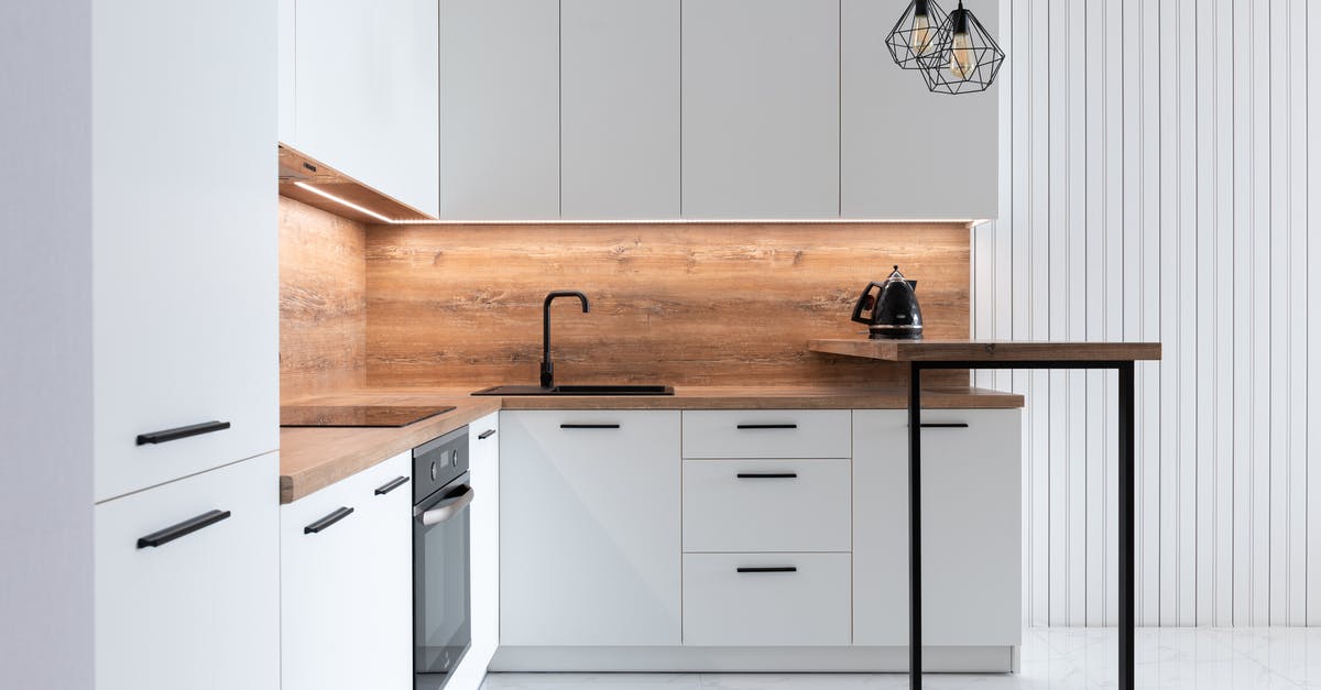 How to clean an electric kettle? - Contemporary interior of modern kitchen with comfortable white furniture and geometrical lamps hanging on ceiling How to clean an electric kettle? - Contemporary interior of modern kitchen with comfortable white furniture and geometrical lamps hanging on ceiling
