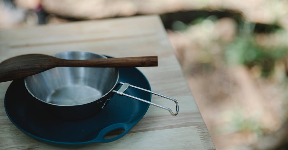 How to clean scrambled eggs from a pan? - High angle of metal pan and wooden spatula placed on plastic plate on table How to clean scrambled eggs from a pan? - High angle of metal pan and wooden spatula placed on plastic plate on table