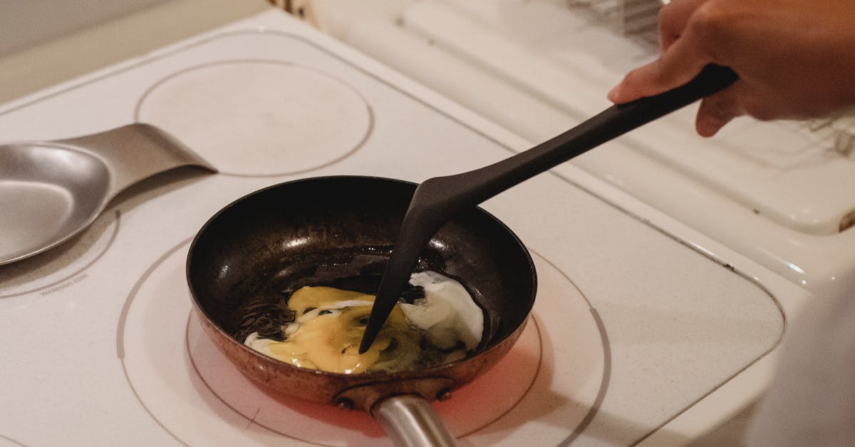 How to clean scrambled eggs from a pan? - Crop unrecognizable person near white stove with black spatula cooking scrambled eggs in kitchen How to clean scrambled eggs from a pan? - Crop unrecognizable person near white stove with black spatula cooking scrambled eggs in kitchen