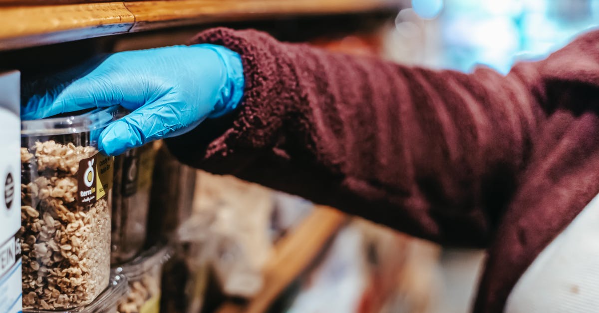 How to clump store-bought granola? - Crop anonymous woman in latex gloves picking food in plastic container while shopping in grocery store