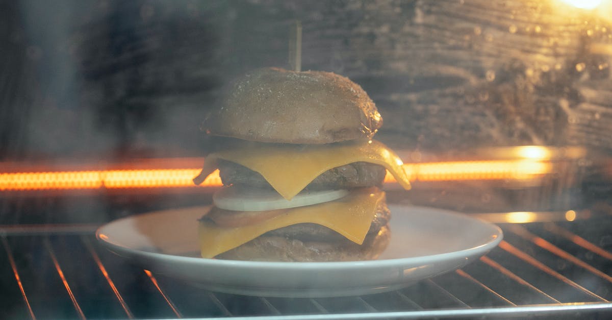 How to convert grilled Beer Can Burger recipe to oven baked - Through glass of tasty burger with cutlet and cheese served on white plate in hot oven on rack while roasting How to convert grilled Beer Can Burger recipe to oven baked - Through glass of tasty burger with cutlet and cheese served on white plate in hot oven on rack while roasting