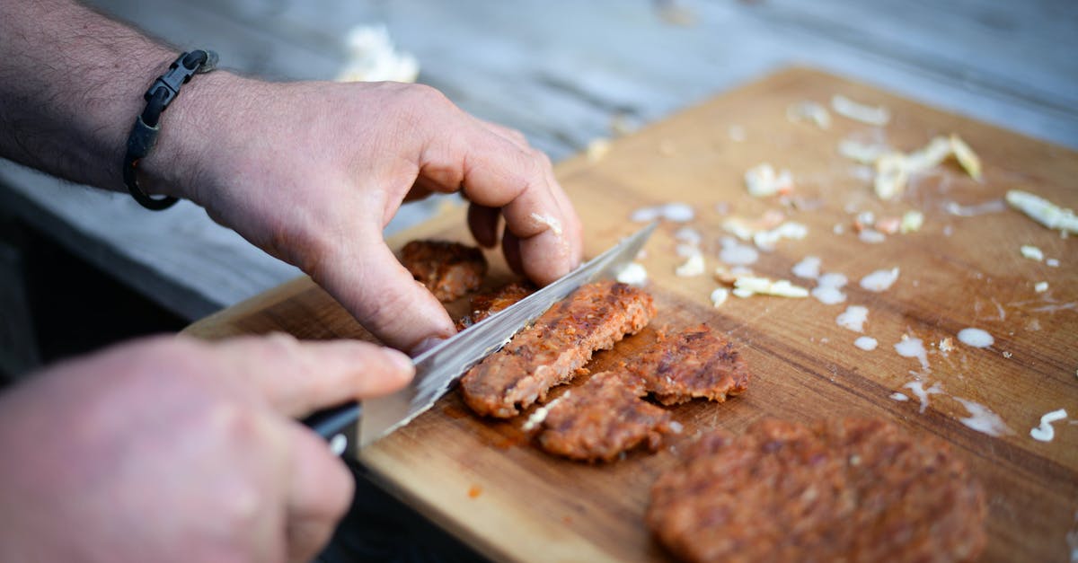 How to cook already cut roast beef - Crop anonymous male cook cutting yummy grilled cutlet on wooden board before serving