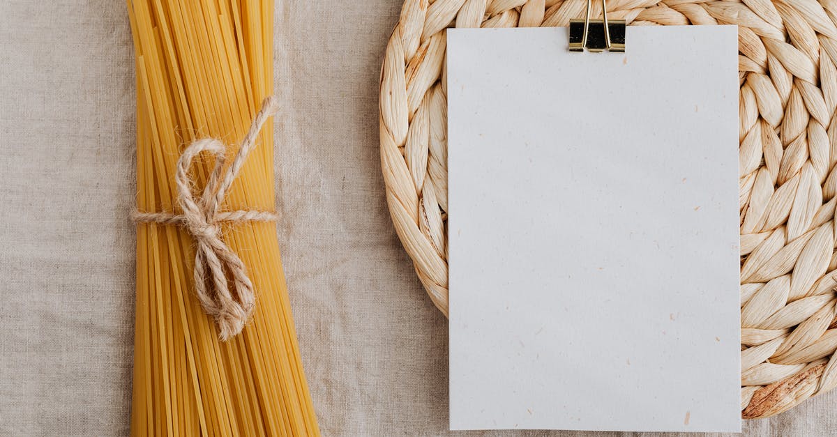 How to cook eye of round roast? - From above of blank paper placed on wicker table mat next to spaghetti tied with bow arranged on table covered with linen tablecloth suitable for recipe or ingredient listing