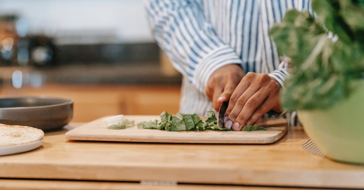 How to cook flatbread without oil? - Faceless ethnic man cutting spinach leaves in house kitchen How to cook flatbread without oil? - Faceless ethnic man cutting spinach leaves in house kitchen