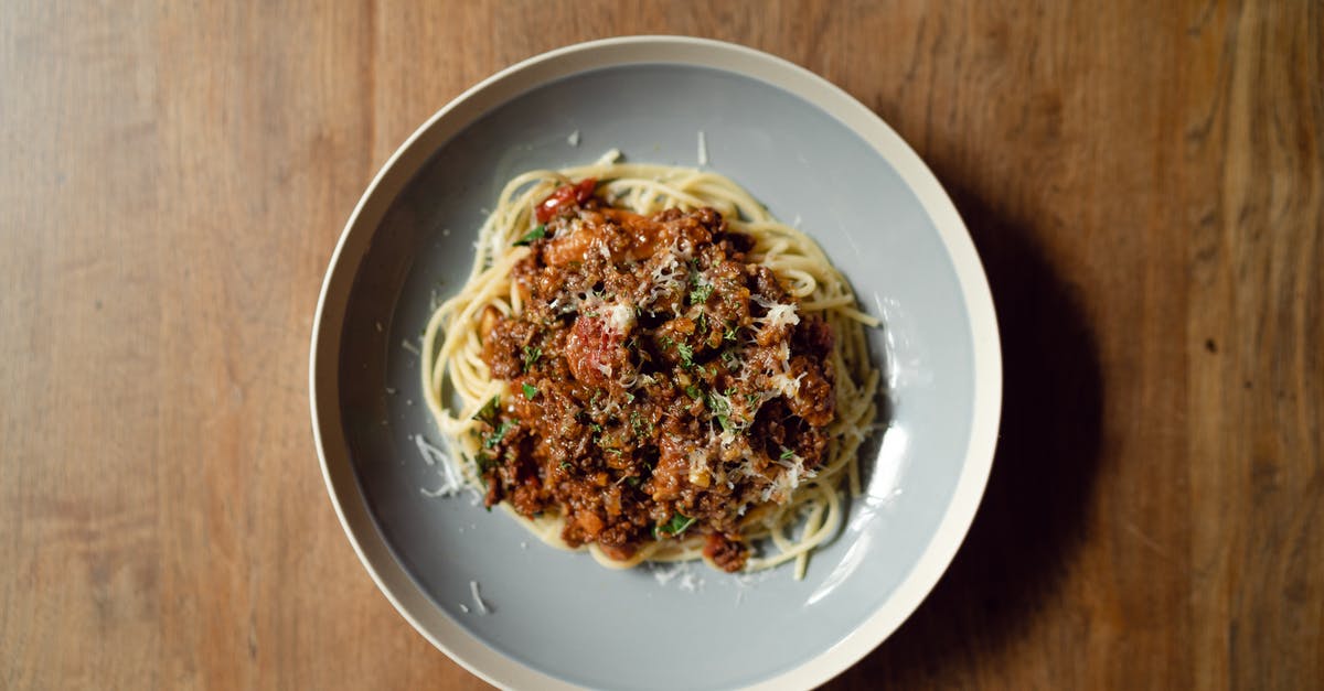 How to cook Parmesan Cheese into a broth without making globs? - Top view of round plate with delicious Italian pasta Bolognaise garnished with grated parmesan cheese placed on wooden table How to cook Parmesan Cheese into a broth without making globs? - Top view of round plate with delicious Italian pasta Bolognaise garnished with grated parmesan cheese placed on wooden table