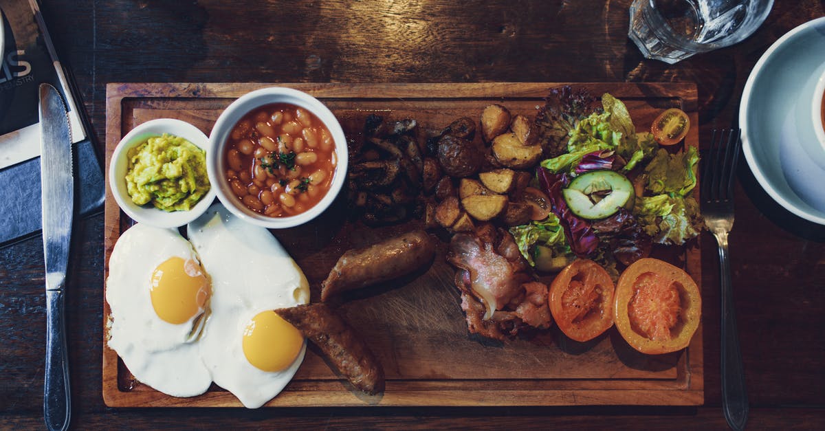 How to cook roast potatoes at low temperatures? - Top view of delicious fried eggs and vegetables with sausages and beans on wooden tray with fork and knife How to cook roast potatoes at low temperatures? - Top view of delicious fried eggs and vegetables with sausages and beans on wooden tray with fork and knife