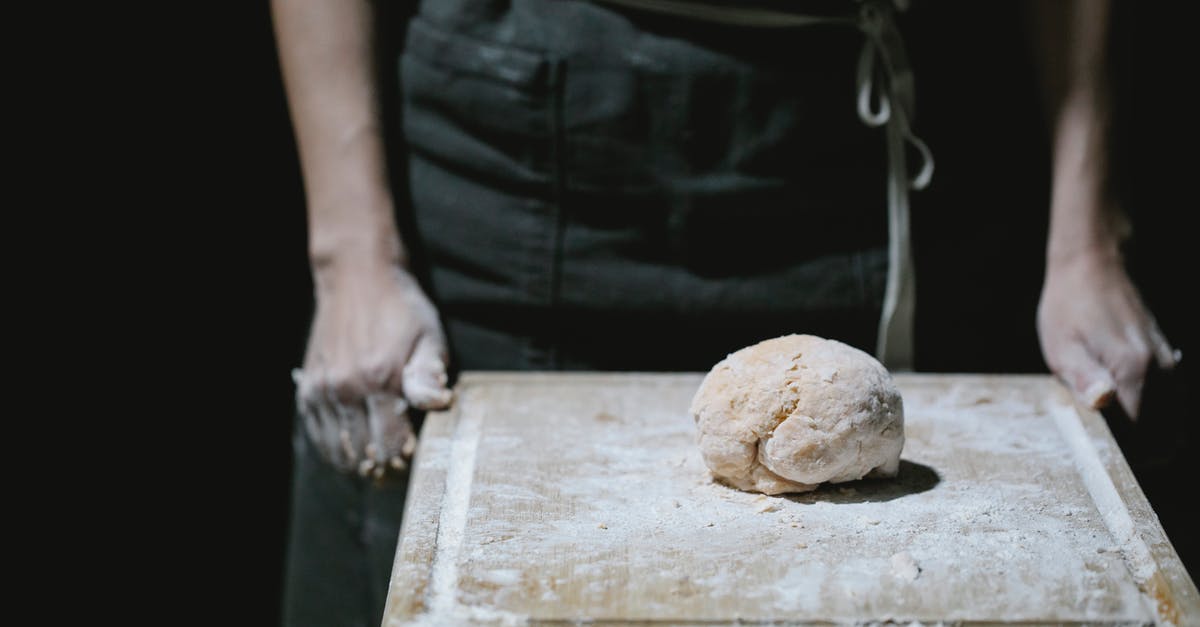 How to cook the food such that no acrylamide is formed? - Baker in apron standing at table with dough How to cook the food such that no acrylamide is formed? - Baker in apron standing at table with dough