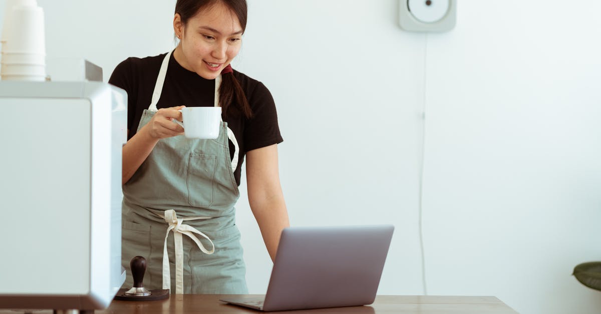 How to cook using a wok - Cheerful woman with cup of beverage working on laptop