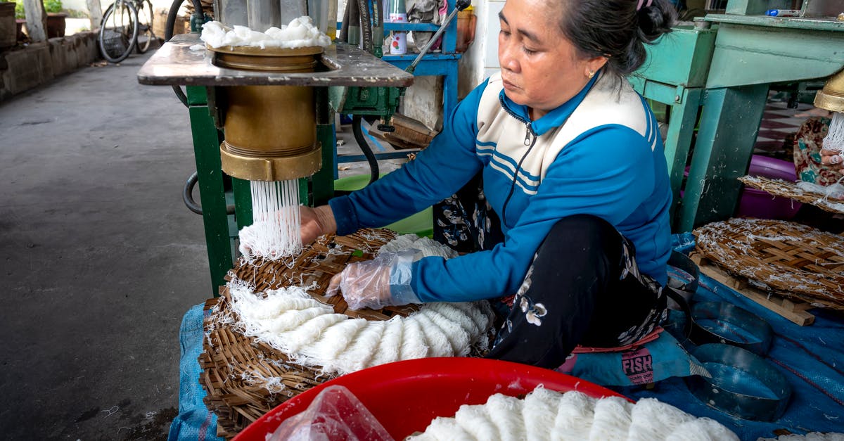 How to create the best veg noodles? - Ethnic lady making noodle on machine in factory How to create the best veg noodles? - Ethnic lady making noodle on machine in factory