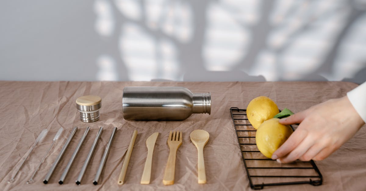 How to efficiently squeeze lemons by hand? - A Person Holding a Lemon on a Table with Utensils and Tumbler