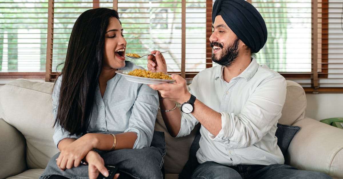 How to Feed a Sour Culture - Delighted ethnic couple having meal on sofa in living room How to Feed a Sour Culture - Delighted ethnic couple having meal on sofa in living room