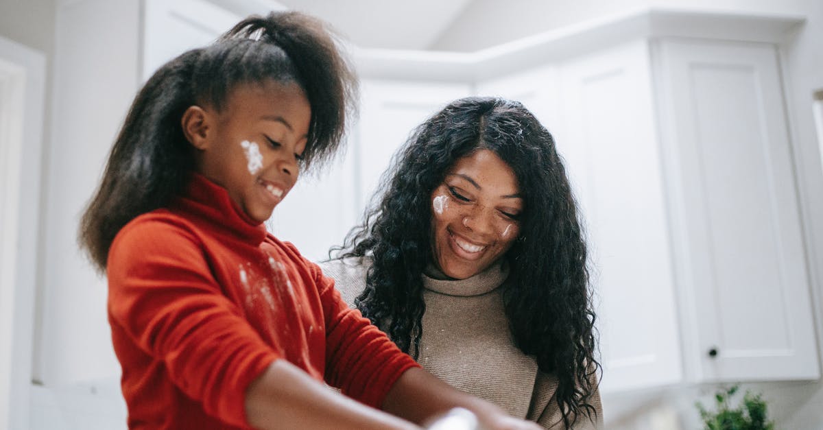 How to get flour quesadilla light and crispy? - Cheerful messy African American child with flour on face cooking with parent at home