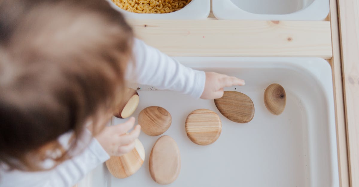 How to get rid of the bitterness in home-made mustard - Crop anonymous child getting brown stones from white container at home How to get rid of the bitterness in home-made mustard - Crop anonymous child getting brown stones from white container at home
