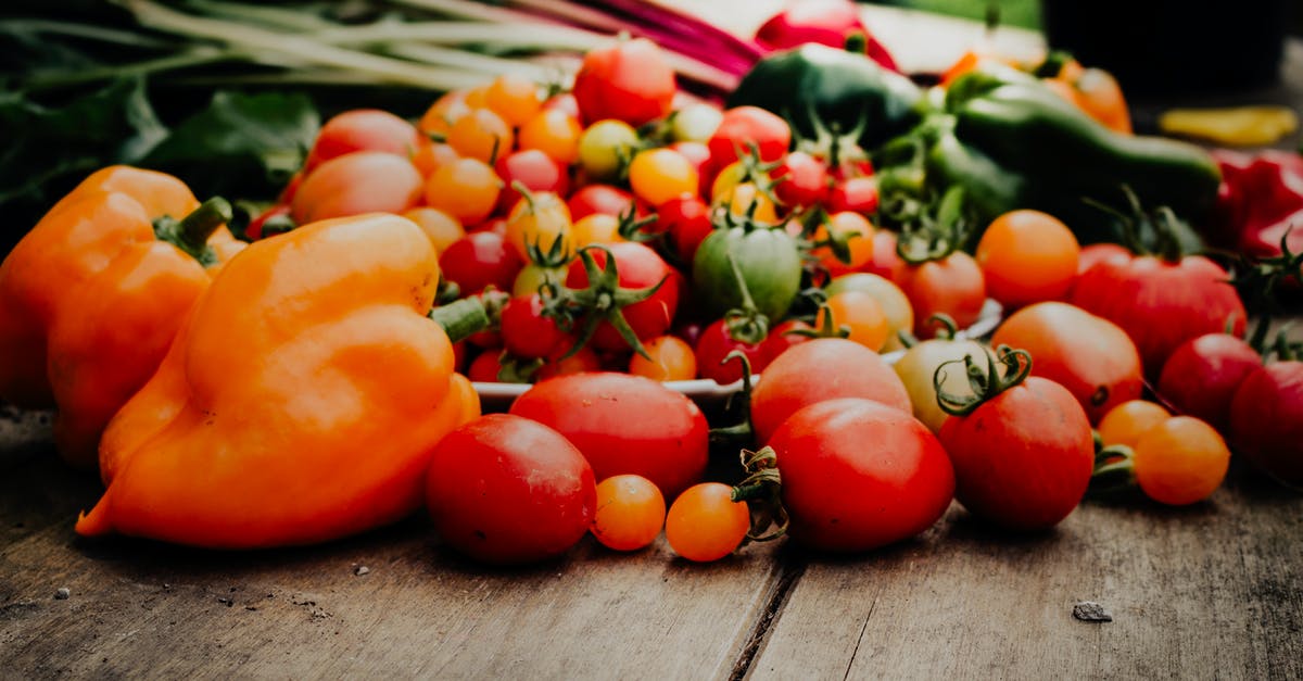 How to harvest peppers and tomatoes for later use in sauces without harming taste [duplicate] - Close-Up Shot of Peppers and Tomatoes on a Wooden Surface