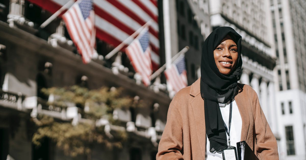 How to identify CTC tea? - From below of cheerful African American female ambassador with folder wearing hijab and id card looking away while standing near building with American flags on blurred background How to identify CTC tea? - From below of cheerful African American female ambassador with folder wearing hijab and id card looking away while standing near building with American flags on blurred background