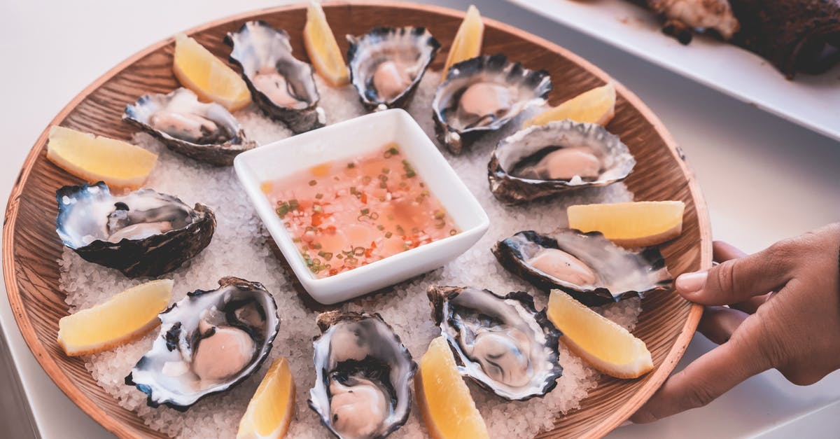 How to make a sauce using sugared citrus rinds? - Anonymous person serving plate of fresh oysters with sauce and lemons on table How to make a sauce using sugared citrus rinds? - Anonymous person serving plate of fresh oysters with sauce and lemons on table