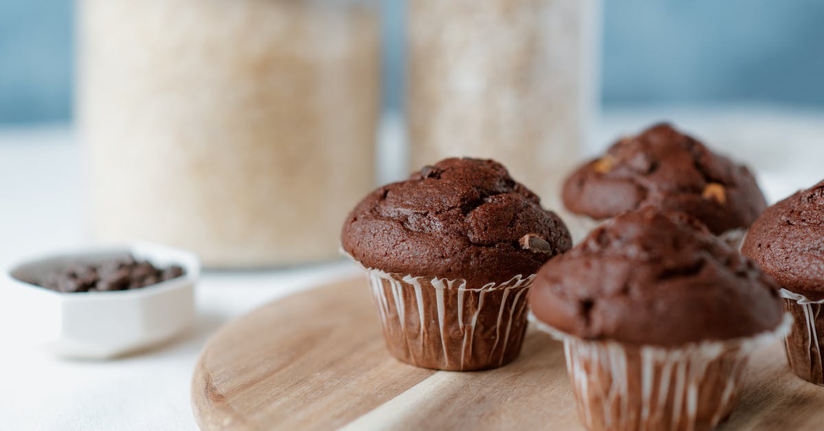How to make modeling chocolate shiny? - Tasty soft muffins with chocolate chips in paper liners on table on blurred background