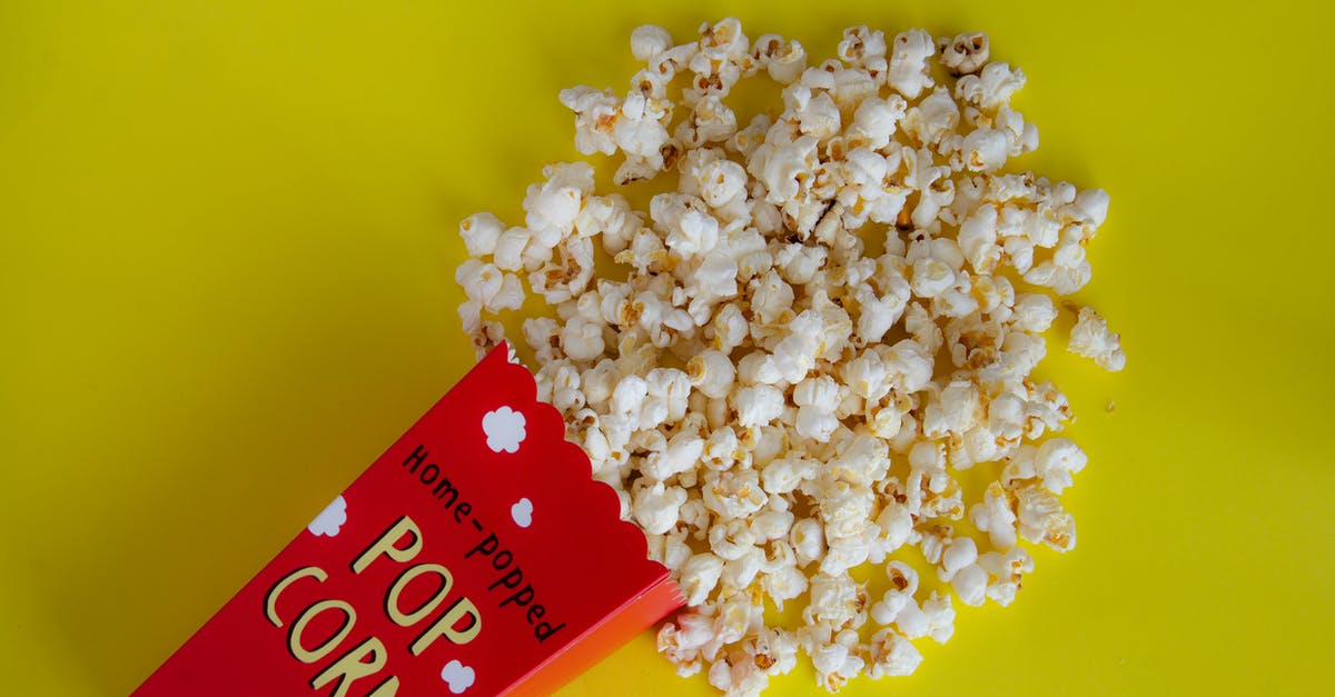 How to make perfect crunchy popcorn? - Pack with spilled popcorn on yellow background How to make perfect crunchy popcorn? - Pack with spilled popcorn on yellow background