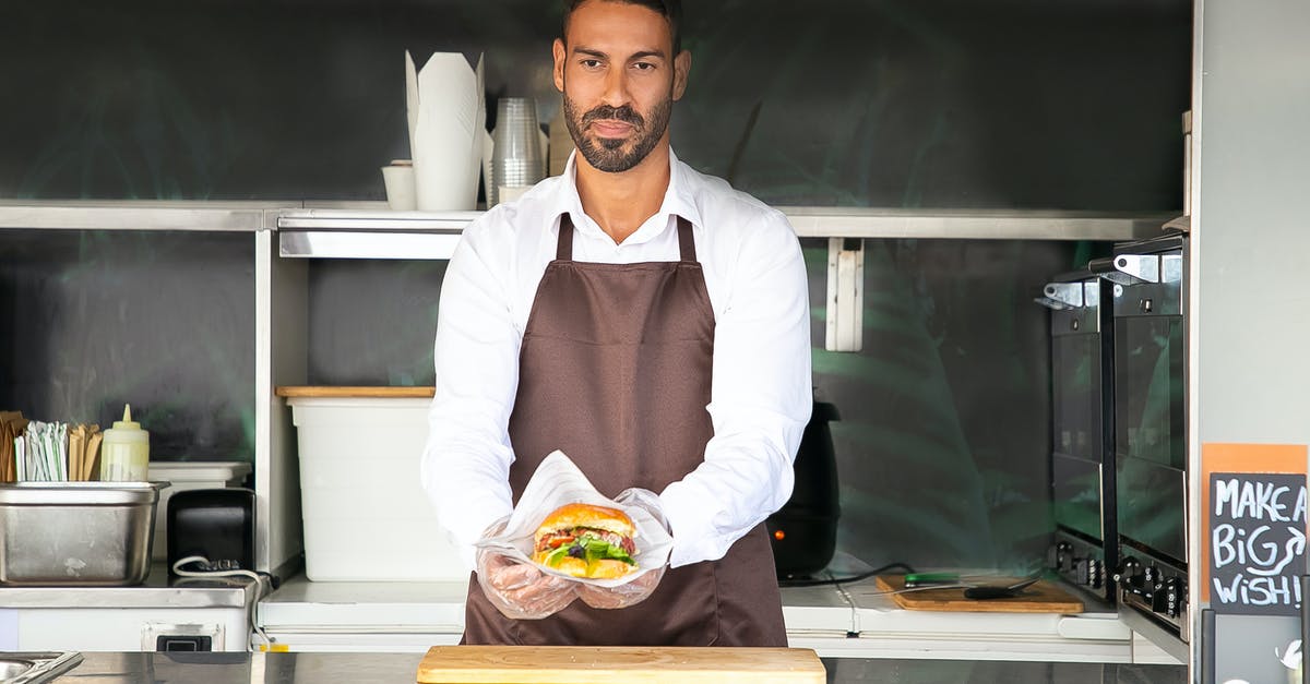 How to make professional style burger buns? - Young ethnic chef showing tasty burger in road cafe How to make professional style burger buns? - Young ethnic chef showing tasty burger in road cafe