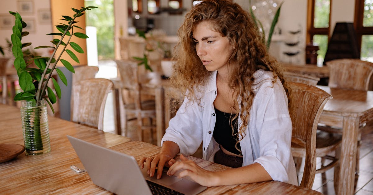 How to make restaurant style poppadoms - Content female customer with long curly hair wearing casual outfit sitting at wooden table with netbook in classic interior restaurant while making online order