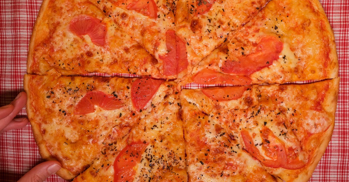 How to make (vegan) cheese saltier? - Top view of crop faceless person at table with pizza slices with tomatoes and cheese with seasoning