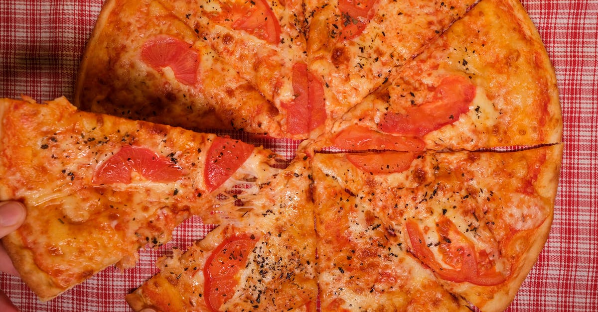 How to mimic Giordano's Pizza CRUST at home ? (part 1) - Top view of crop anonymous person taking slice of yummy pizza with tomato and oregano placed on checkered tablecloth How to mimic Giordano's Pizza CRUST at home ? (part 1) - Top view of crop anonymous person taking slice of yummy pizza with tomato and oregano placed on checkered tablecloth