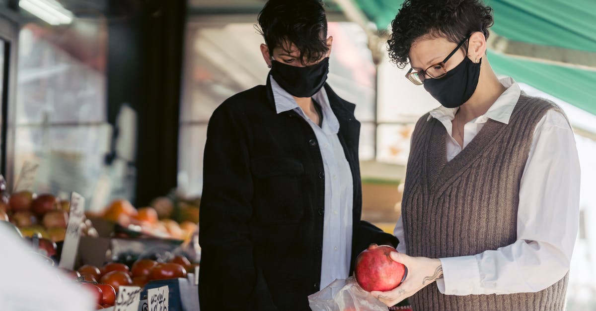 How to not buy the bad apple? - Concentrated young female friends in casual clothes and medical masks choosing fruits in local street food market on sunny day during coronavirus pandemic How to not buy the bad apple? - Concentrated young female friends in casual clothes and medical masks choosing fruits in local street food market on sunny day during coronavirus pandemic
