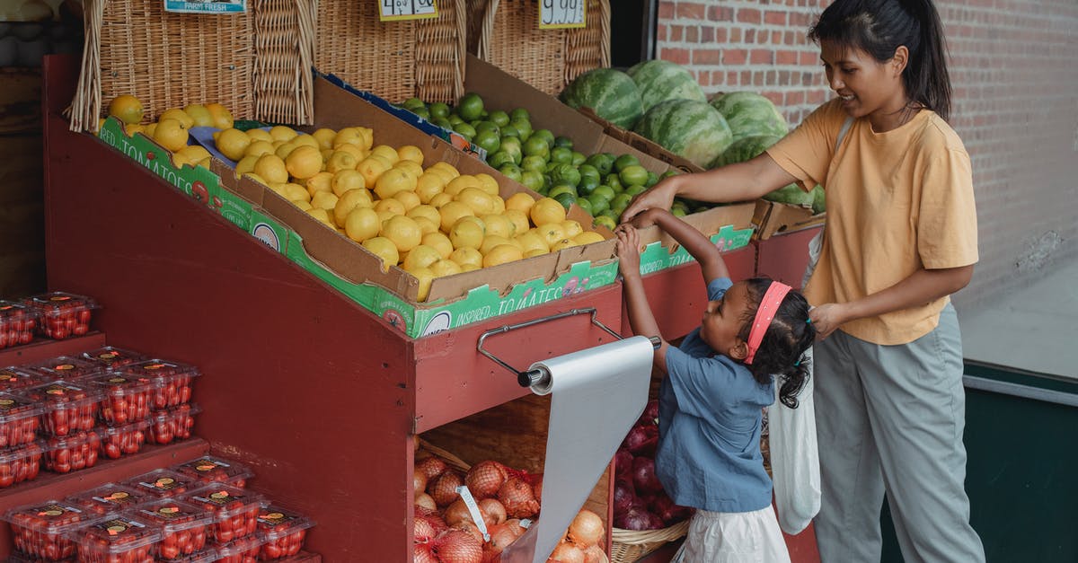 How to not buy the bad apple? - Small ethnic girl taking fruits from box with mother How to not buy the bad apple? - Small ethnic girl taking fruits from box with mother