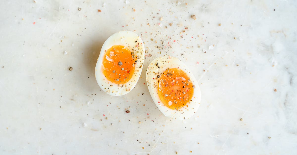 How to peel hard boiled eggs easily? - Top view of halved soft boiled egg placed on marble table and spiced with salt and pepper How to peel hard boiled eggs easily? - Top view of halved soft boiled egg placed on marble table and spiced with salt and pepper