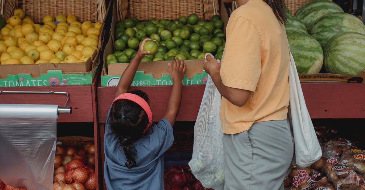 How to pick a good mango at a local store? - Ethnic girl choosing fruit from box in bazaar with mother How to pick a good mango at a local store? - Ethnic girl choosing fruit from box in bazaar with mother