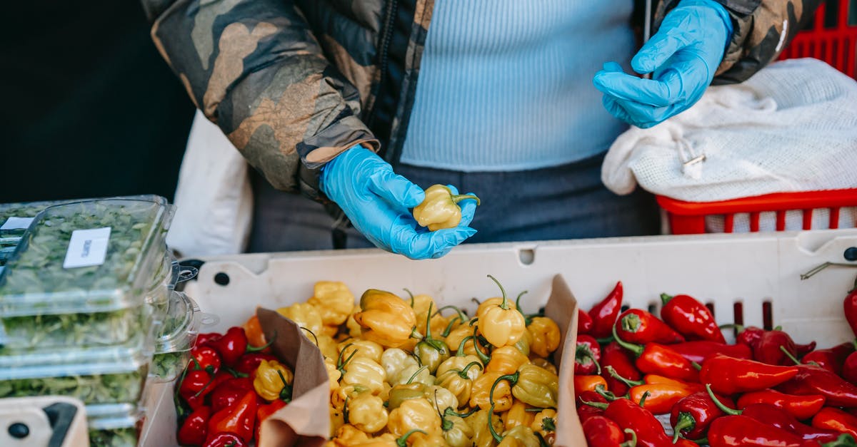 How to pick good clementines and mandarins at the supermarket? - Crop anonymous person in latex gloves carrying market basket and choosing ripe yellow and red capsicums in vegetable supermarket