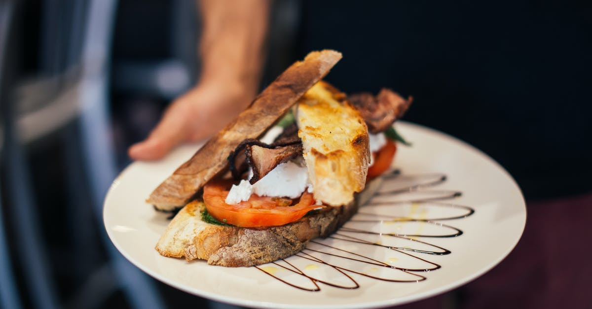 How to poach an egg without vinegar? - From above of crop unrecognizable waiter holding plate of appetizing sandwich with bacon tomatoes and poached eggs in crispy toasted bread