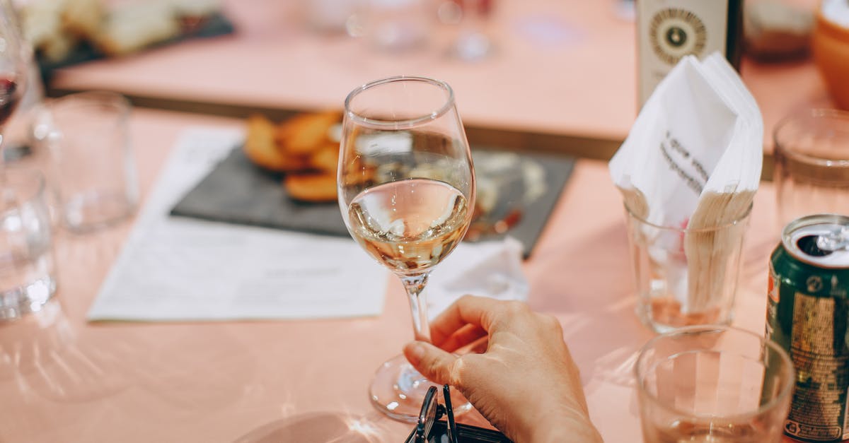 How to polish wine glasses if my hand cannot reach in? - Person Holding Wine Glass Near Clear Shot Glasses