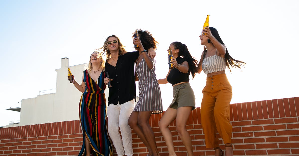 How to preserve this alcohol free herbal bitter? - Low angle full body of multiracial friends having party with raised arms while celebrating together and drinking beer on rooftop