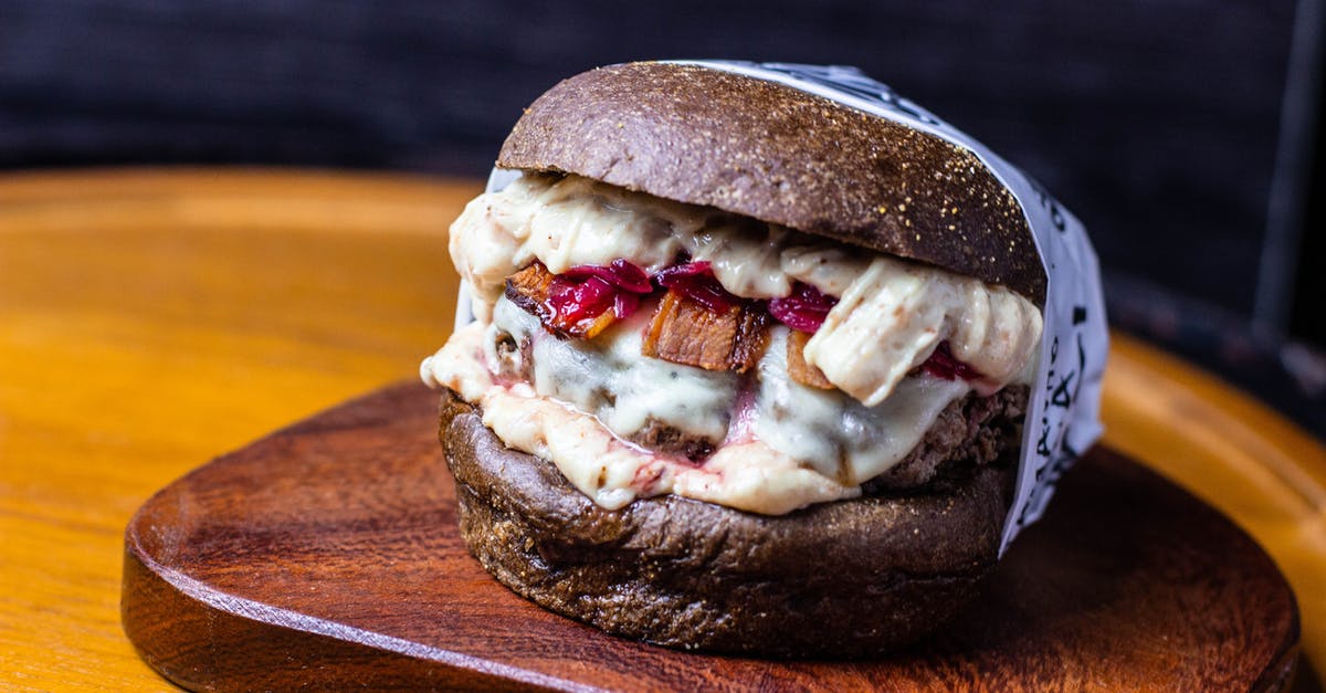 How to prevent bursting from cheese stuffed beef patties? - Delectable hamburger with cheese sauce served on wooden board How to prevent bursting from cheese stuffed beef patties? - Delectable hamburger with cheese sauce served on wooden board