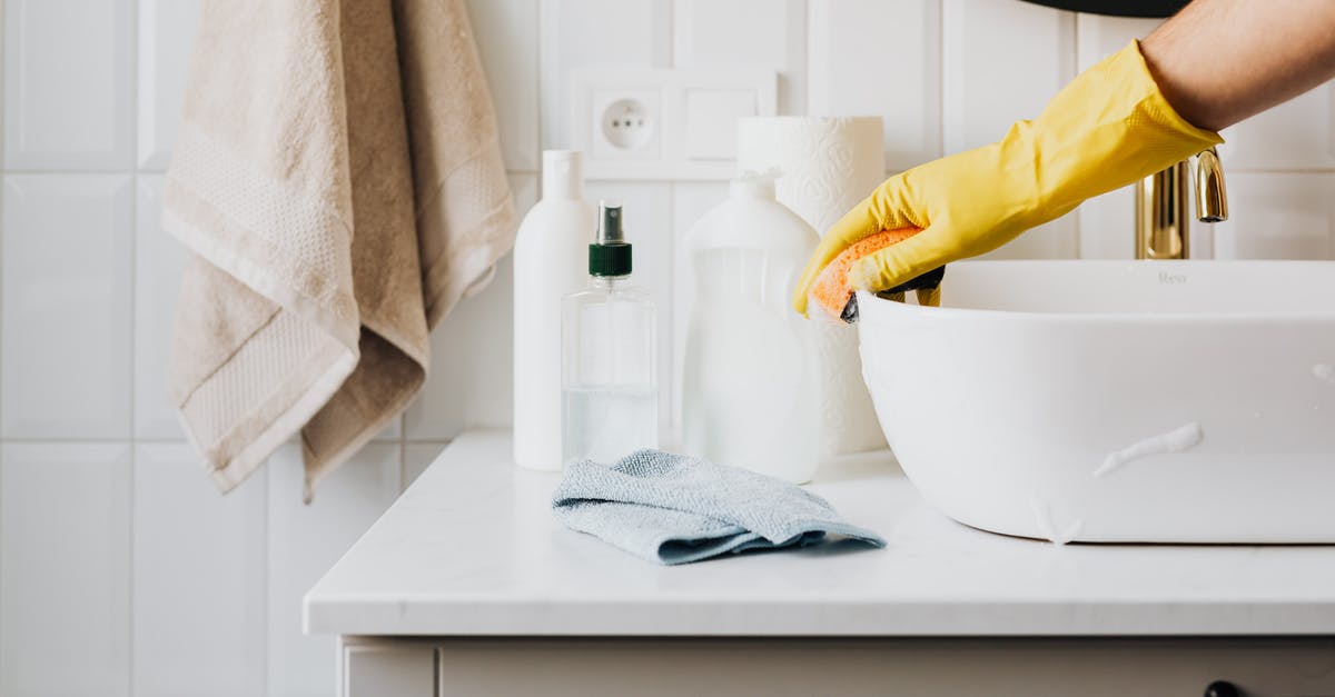 How to properly disinfect surfaces - Person in glove wiping surface of sink in modern bathroom How to properly disinfect surfaces - Person in glove wiping surface of sink in modern bathroom