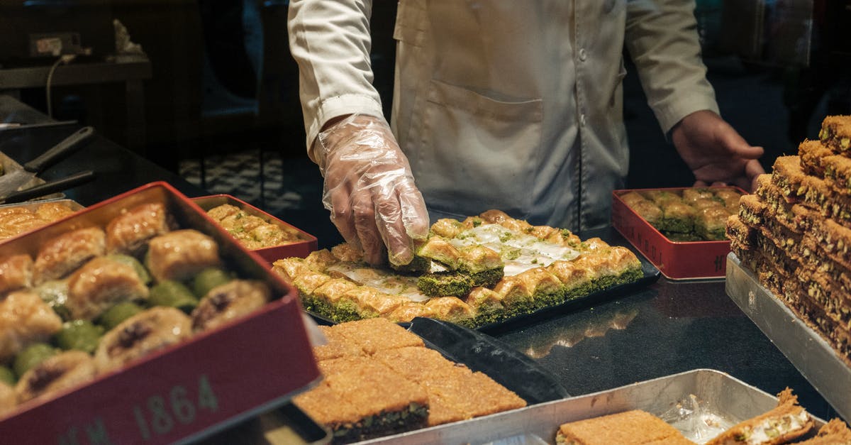 How to put stuff inside baked sandwich and bread? - From above of anonymous crop male in gloves and white robe putting delicious fresh sweet dessert in container in local bakery shop