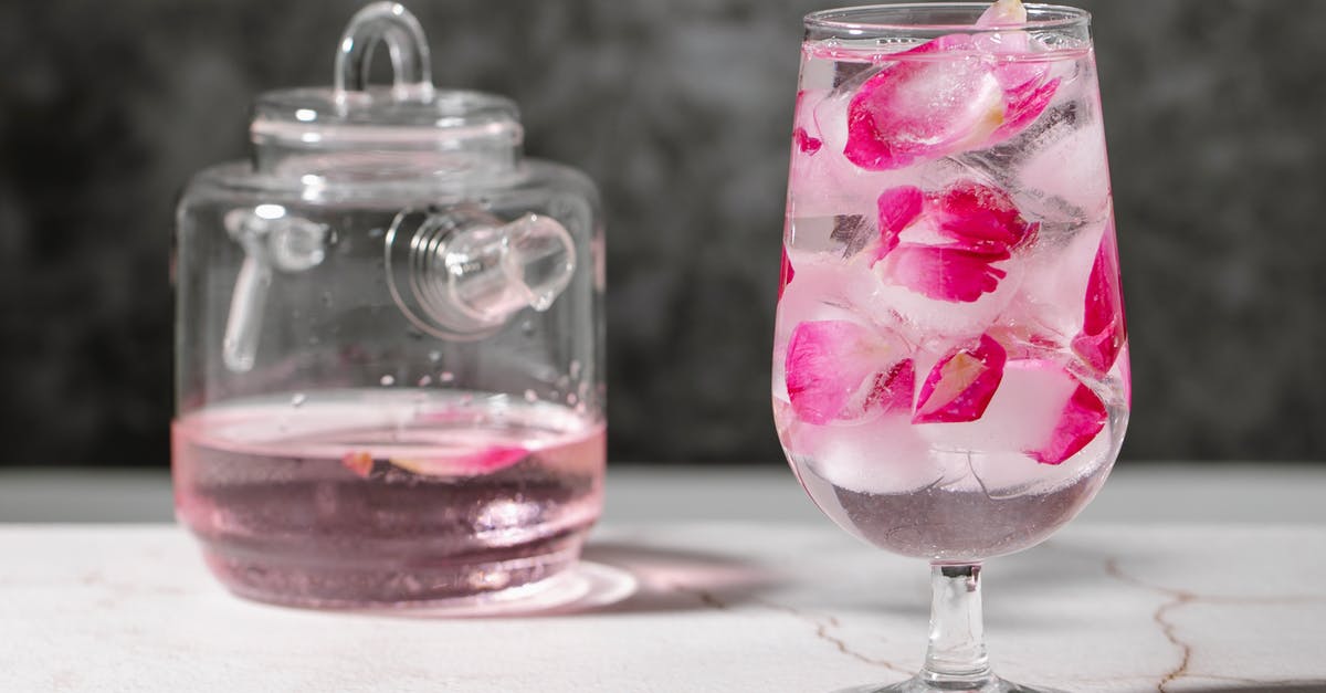 How to refresh a frozen bagel - Crystal glass full of fresh beverage with pink rose petals and ice cubes place on table near jar with drink How to refresh a frozen bagel - Crystal glass full of fresh beverage with pink rose petals and ice cubes place on table near jar with drink