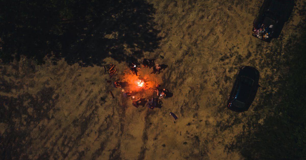 How to Remove Burned-on Grease from Stove - Drone view of group of friends spending time together by flaming bonfire in woodland at night