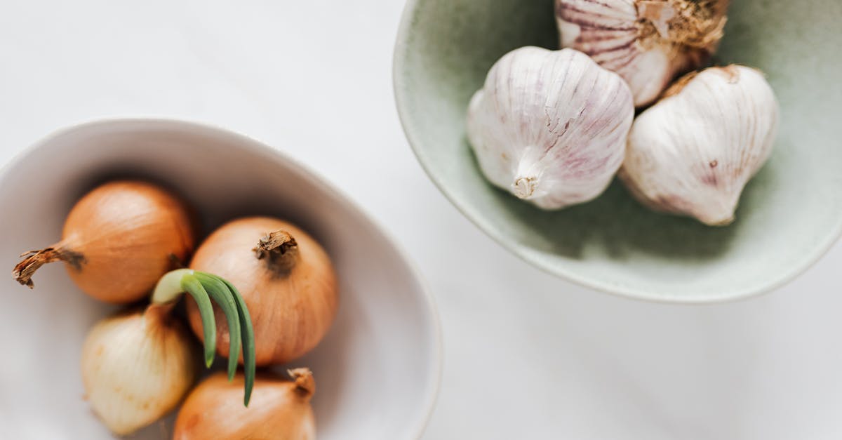 How to remove dirt from inside green/spring onions? - Top view of ceramic bowls of garlic bulbs and onions with green sprouts on white marble table How to remove dirt from inside green/spring onions? - Top view of ceramic bowls of garlic bulbs and onions with green sprouts on white marble table