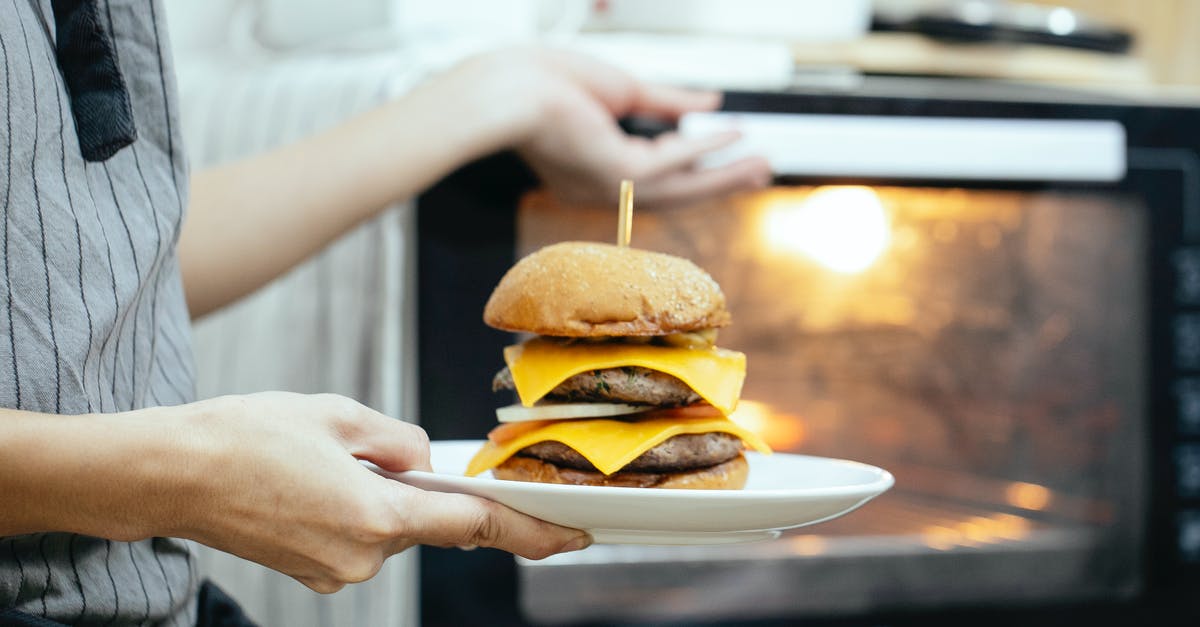 How to roast chestnuts on an open fire? - Unrecognizable person with plate of burger in hand opening door of oven to roast food while cooking in kitchen on blurred background How to roast chestnuts on an open fire? - Unrecognizable person with plate of burger in hand opening door of oven to roast food while cooking in kitchen on blurred background