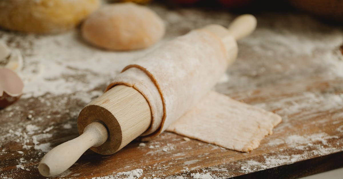 How to smooth a wooden rolling pin - Wooden rolling pin with soft thin dough on table with spilled flour in kitchen How to smooth a wooden rolling pin - Wooden rolling pin with soft thin dough on table with spilled flour in kitchen