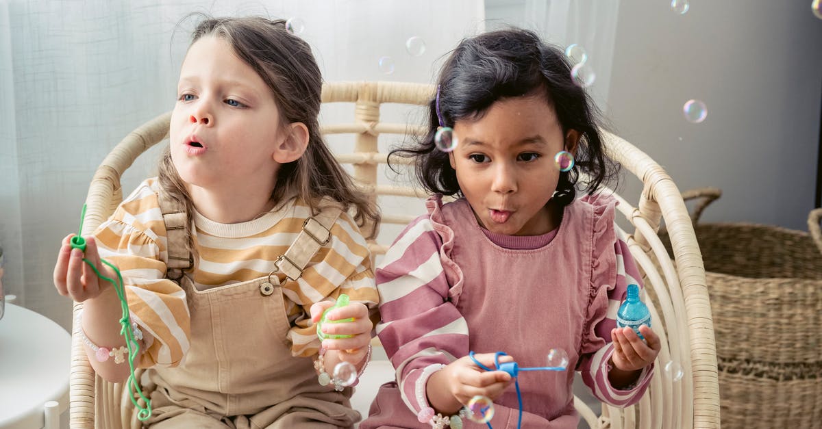How to stick oreo biscuits together to make a tower? - Carefree multiracial girls blowing soap bubbles in armchair at home How to stick oreo biscuits together to make a tower? - Carefree multiracial girls blowing soap bubbles in armchair at home