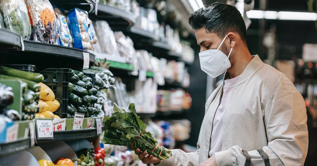 How to Store Fresh Herbs - Young ethnic guy buying bunch of fresh spinach in supermarket