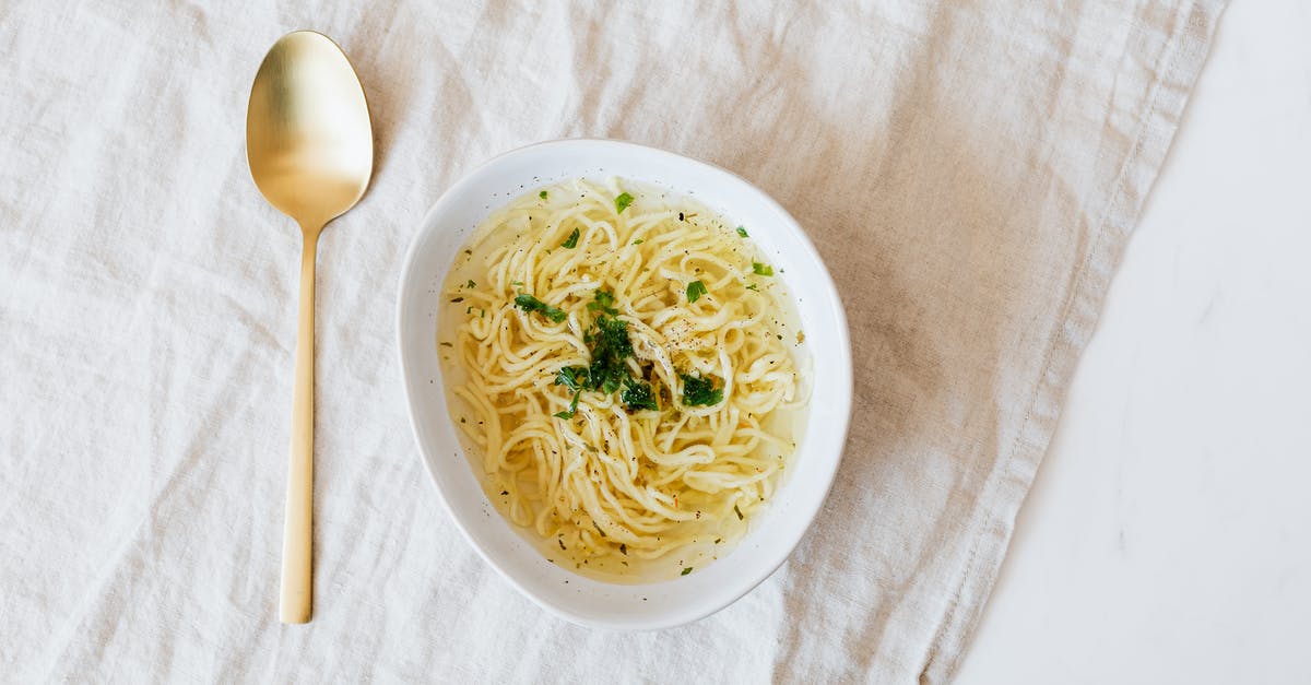 How to substitute chicken broth in a vegetarian soup? - Top view of bowl with yummy noodle soup with greens and golden spoon placed on rumpled linen cloth on marble table How to substitute chicken broth in a vegetarian soup? - Top view of bowl with yummy noodle soup with greens and golden spoon placed on rumpled linen cloth on marble table