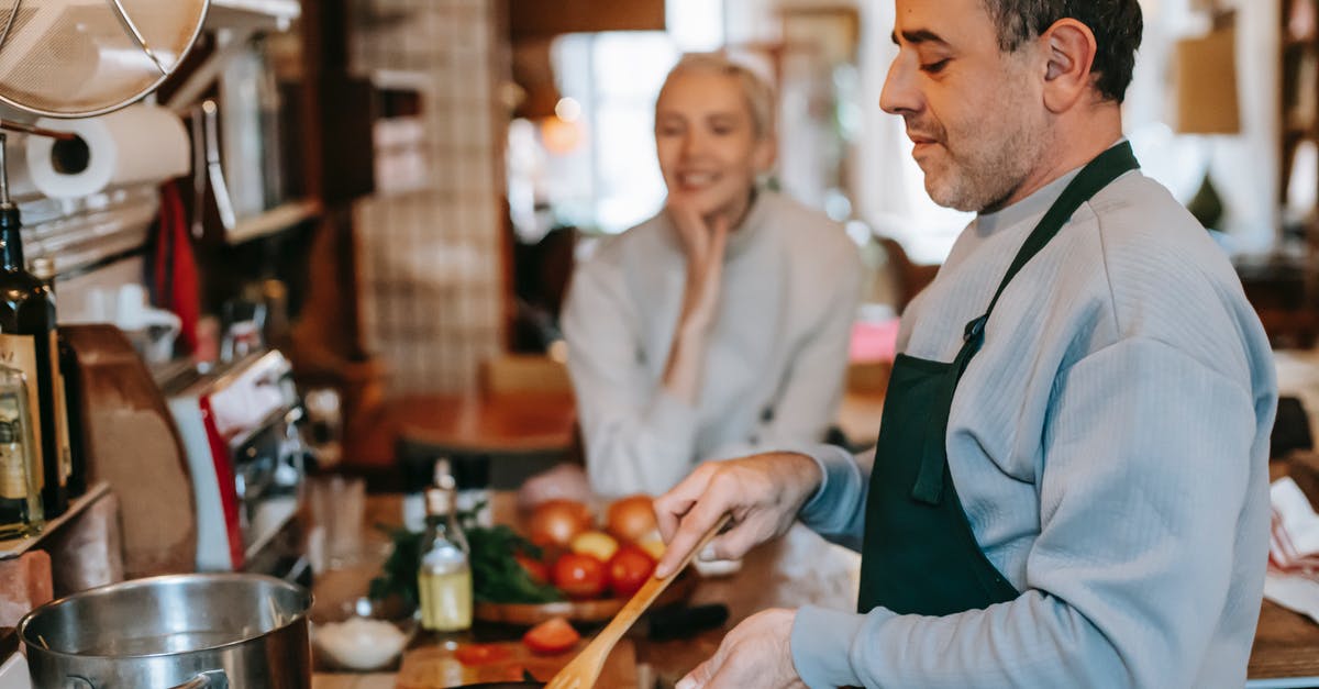 How to tell if stir fry lamb is done? - Crop male stirring tasty meatballs in pan while preparing lunch against smiling female beloved at home